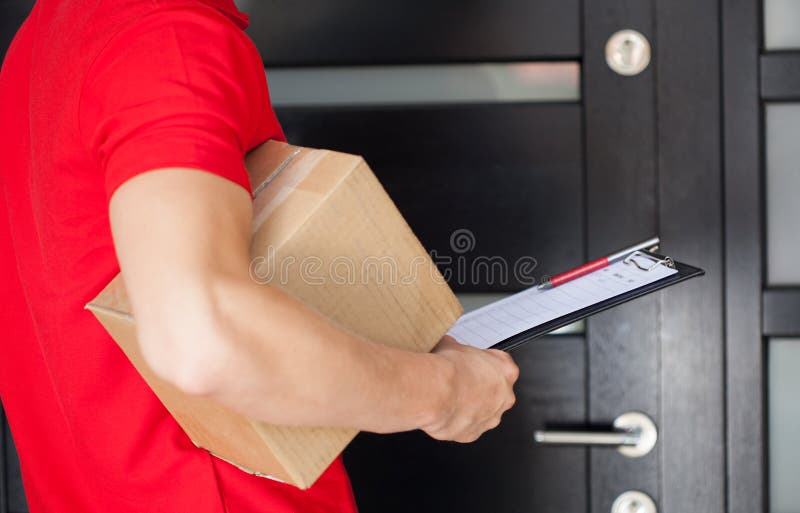 Delivery man at front door. Delivery guy waiting at front door with a parcel royalty free stock images